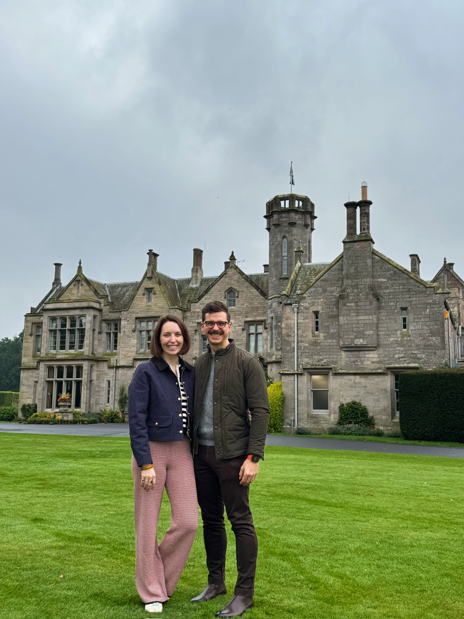 John and his wife standing in front of an old stone building